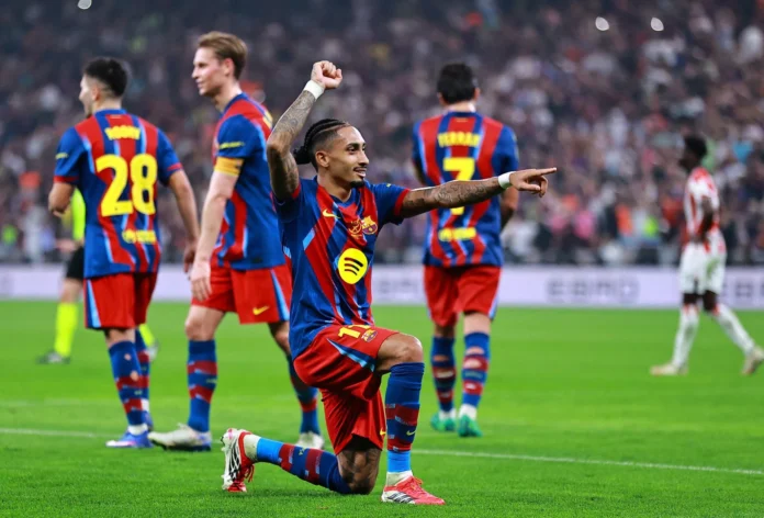لقطة مقربة للنجم البرازيلي رافينيا وهو يحتفل بهدفه الثاني في المباراة، مشيراً بيده للجماهير، بقميص برشلونة الأساسي.